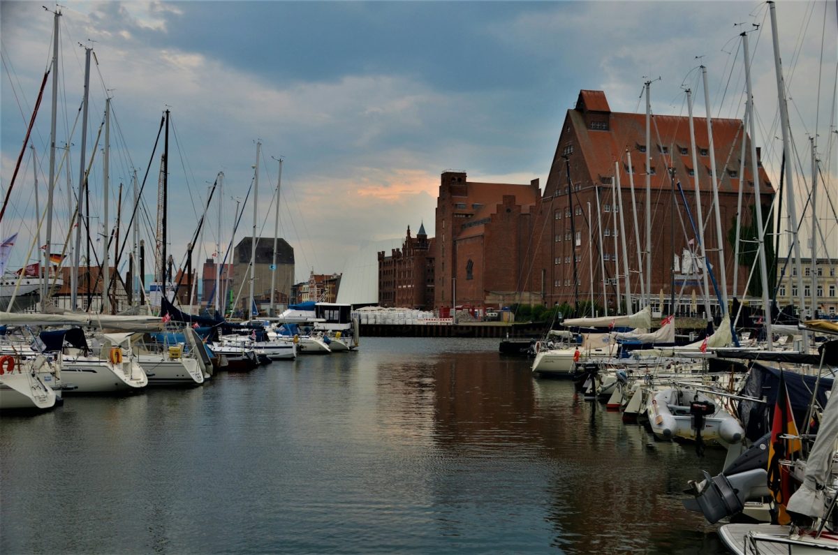 a harbor filled with lots of sailboats under a cloudy sky